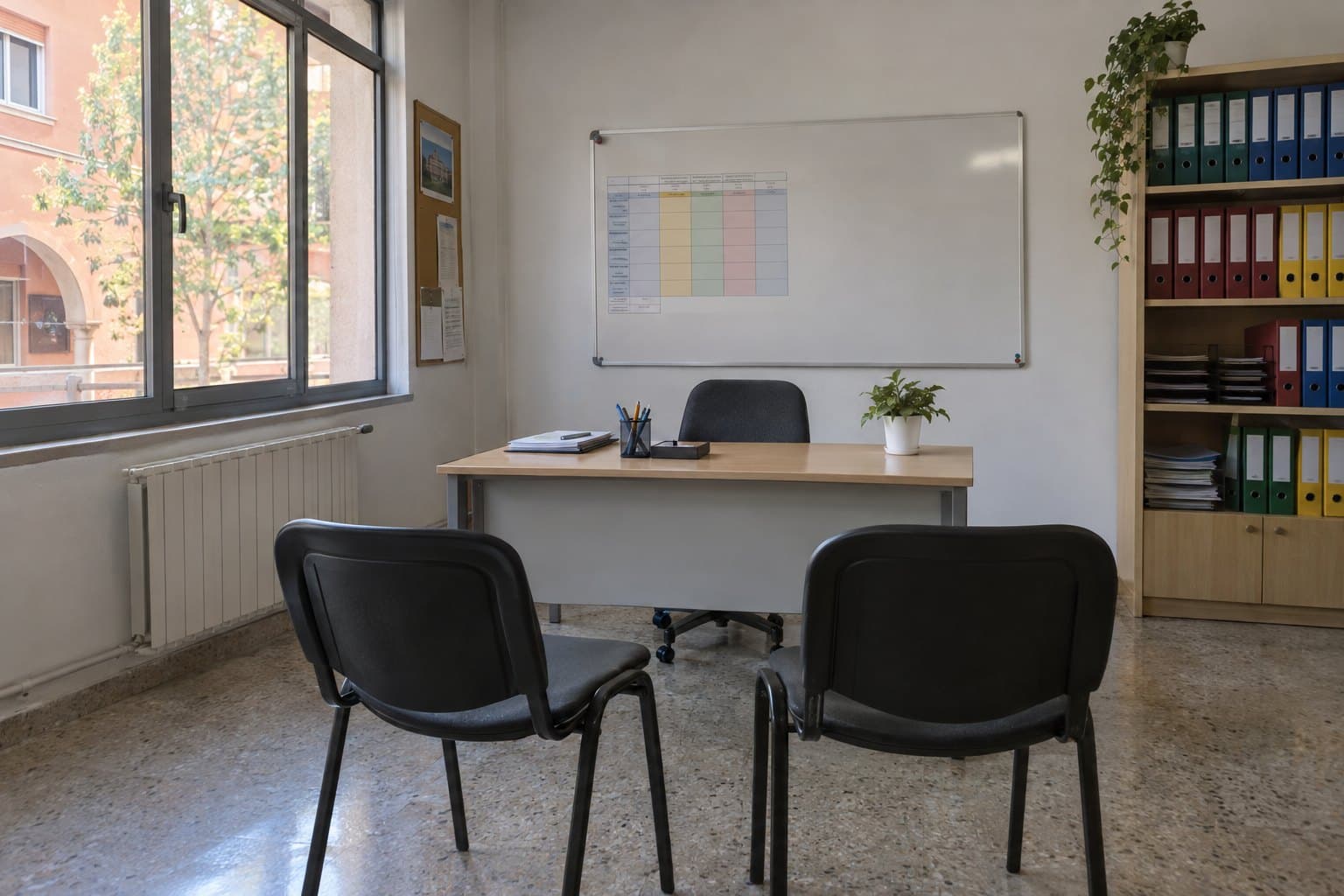 Un aula de una escuela de idiomas: sillas alrededor de una mesa, una pizarra, luz de tarde